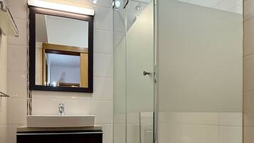 A modern bathroom with a glass-enclosed shower, a vanity with a mirror, and a toilet.