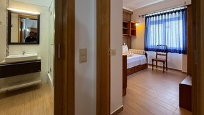 Un dormitorio con cama, mesita de noche y ventana con cortinas.