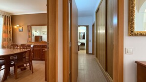 Un pasillo con puertas de madera que dan a un comedor con una mesa y sillas.