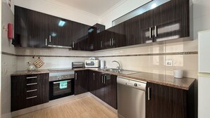 Una cocina moderna con armarios de madera oscura, electrodomésticos de acero inoxidable y encimera de granito.