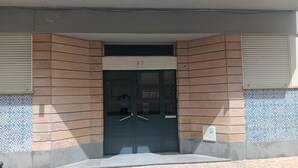 A building entrance with a dark-colored door, a small overhang above the door, and a tiled pattern on the walls.
