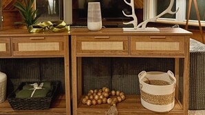 Una consola de madera con cestas tejidas, una lámpara y objetos decorativos.