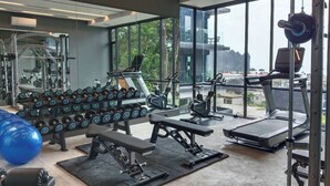 Een moderne sportschool met diverse fitnessapparaten, grote ramen met uitzicht op het omliggende landschap, en een overzichtelijke, nette indeling.