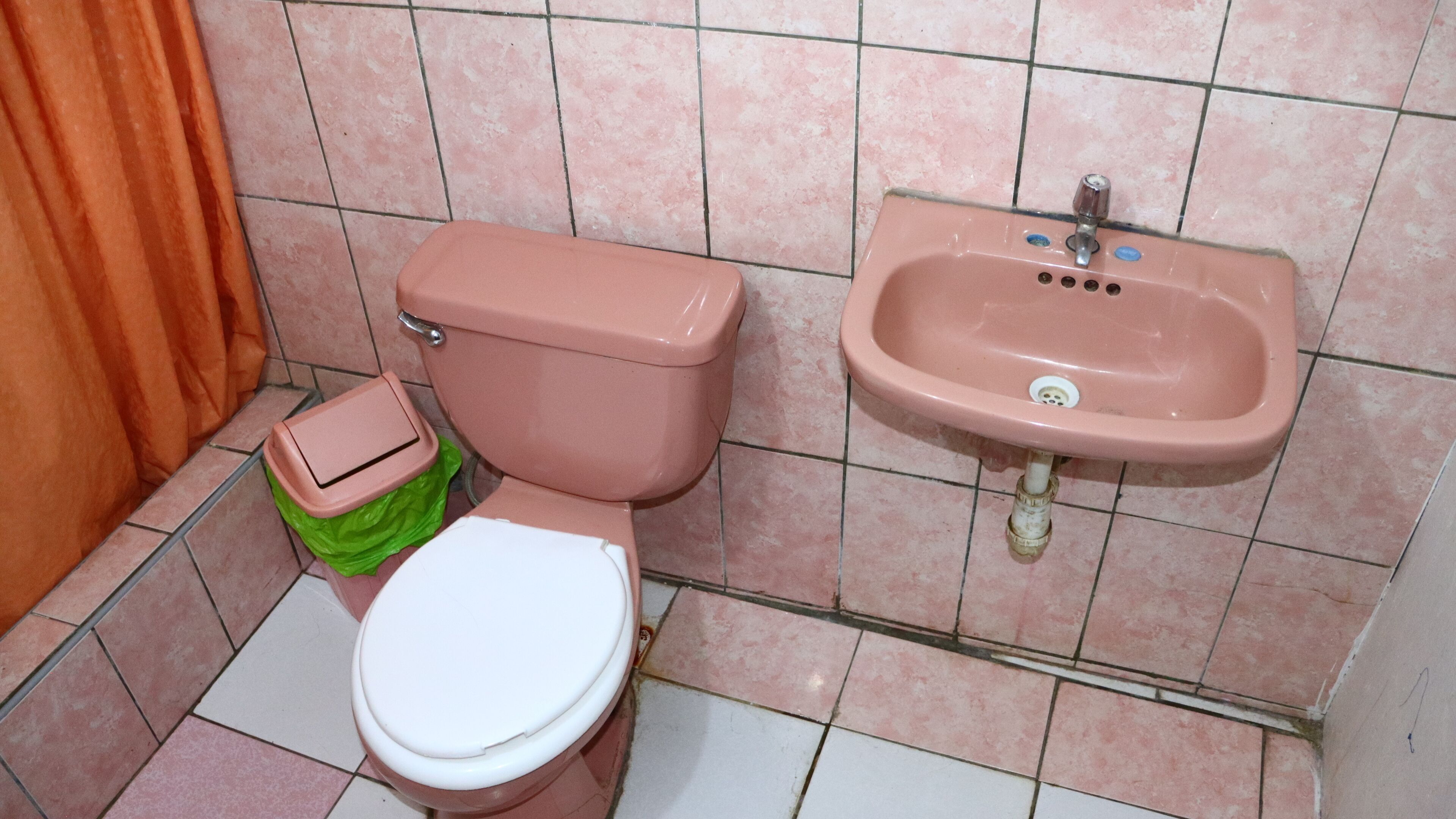 Une salle de bain équipée de toilettes, d’un lavabo et d’une poubelle.
