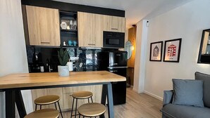 A modern kitchen with wooden cabinets, a black refrigerator, and a bar area with stools.
