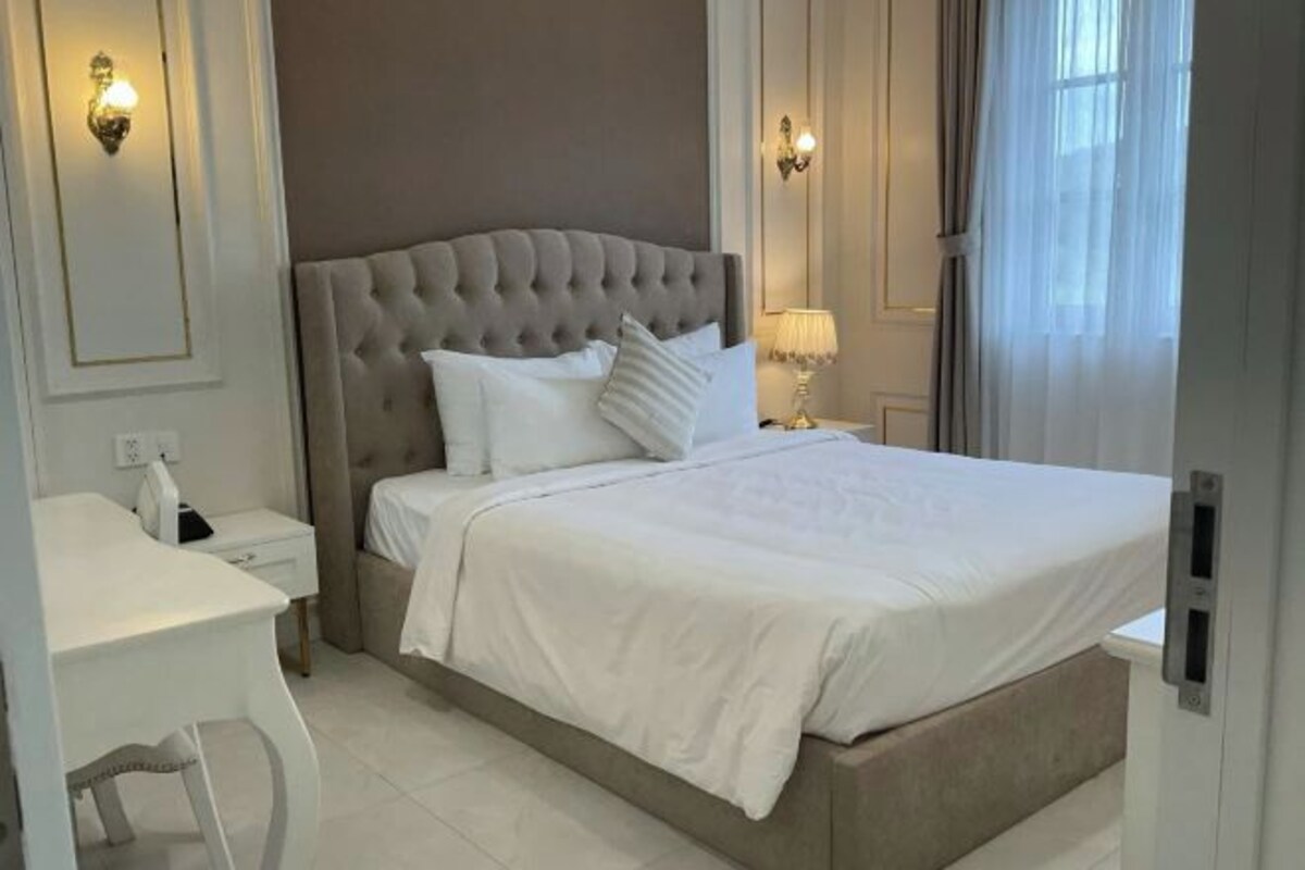 A neatly arranged bedroom with a large bed, a bedside table, and a desk.
