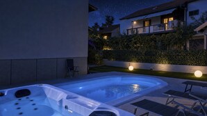 Un jacuzzi con panel de control, una silla de descanso y una mesa.