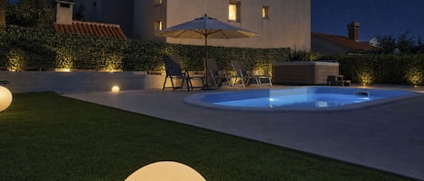 Uma casa moderna com piscina, móveis de exterior e um céu estrelado.