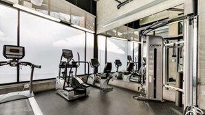 Une salle de sport équipée de machines de cardio, de matériel de musculation et de miroirs.