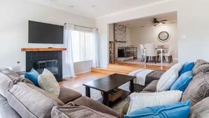Een moderne woonkamer met een open haard, een eethoek en een zichtbare keuken door een open doorgang.