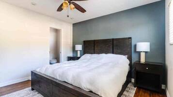 A bedroom with a bed, two bedside tables, a ceiling fan, and a nightstand with a lamp.