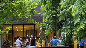 An outdoor reception area with a glass facade, a reception desk, and lush greenery. - Royal Executive Living Garden Executive (Caulfield North)