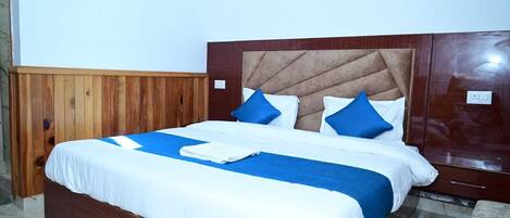 A bed with a wooden headboard, white and blue bedding, and two blue pillows.