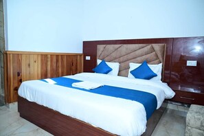 A bed with a wooden headboard, white and blue bedding, and two blue pillows. - The Cedar Bliss (Shimla)