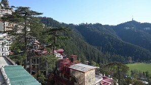 A mountainous area with buildings and a clear sky. - The Cedar Bliss (Shimla)