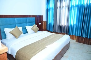 A hotel room with a large bed, wooden headboard, and blue curtains. - The Cedar Bliss (Shimla)