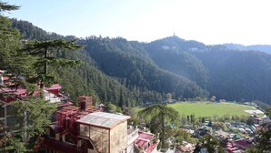 A mountainous landscape with a village and a large open field. - The Cedar Bliss (Shimla)