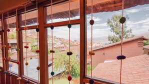 A view through a window with colorful hanging decorations and a glimpse of the surrounding neighborhood. - CHARMING WOODEN APART IN CENTRAL CUSCO (Cusco)