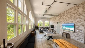 A spacious room with a pool table, comfortable seating, large windows, and a brick wall. - Spacious Private Retreat with Event Spaces (San Diego)