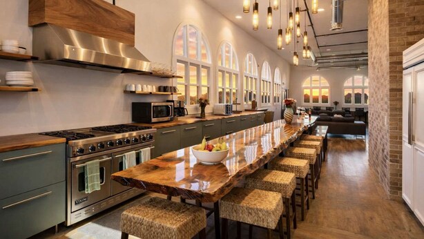 A modern kitchen with a long island, stainless steel appliances, and a brick accent wall. - Spacious Private Retreat with Event Spaces (San Diego)