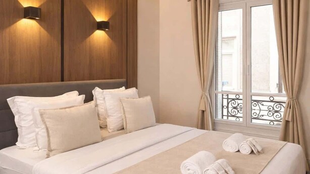 Ein Hotelzimmer mit Bett, Kissen, Decke und Handtüchern.