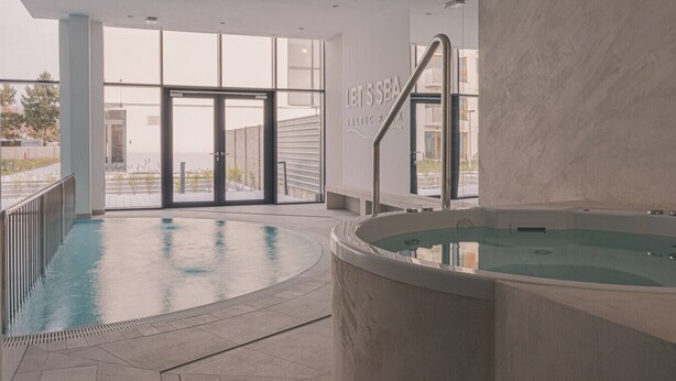 An indoor pool area with a hot tub, large windows, and a sign reading 'LET'S SEA BALTIC SEA.' - Perla | Coastal Comfort | Terrace with Sea View | SPA AccessPerla (Gąski)