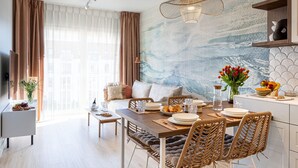 A modern living room with a dining area, a sofa set, a coffee table, and a dining table with chairs. - Perla | Coastal Comfort | Terrace with Sea View | SPA AccessPerla (Gąski)