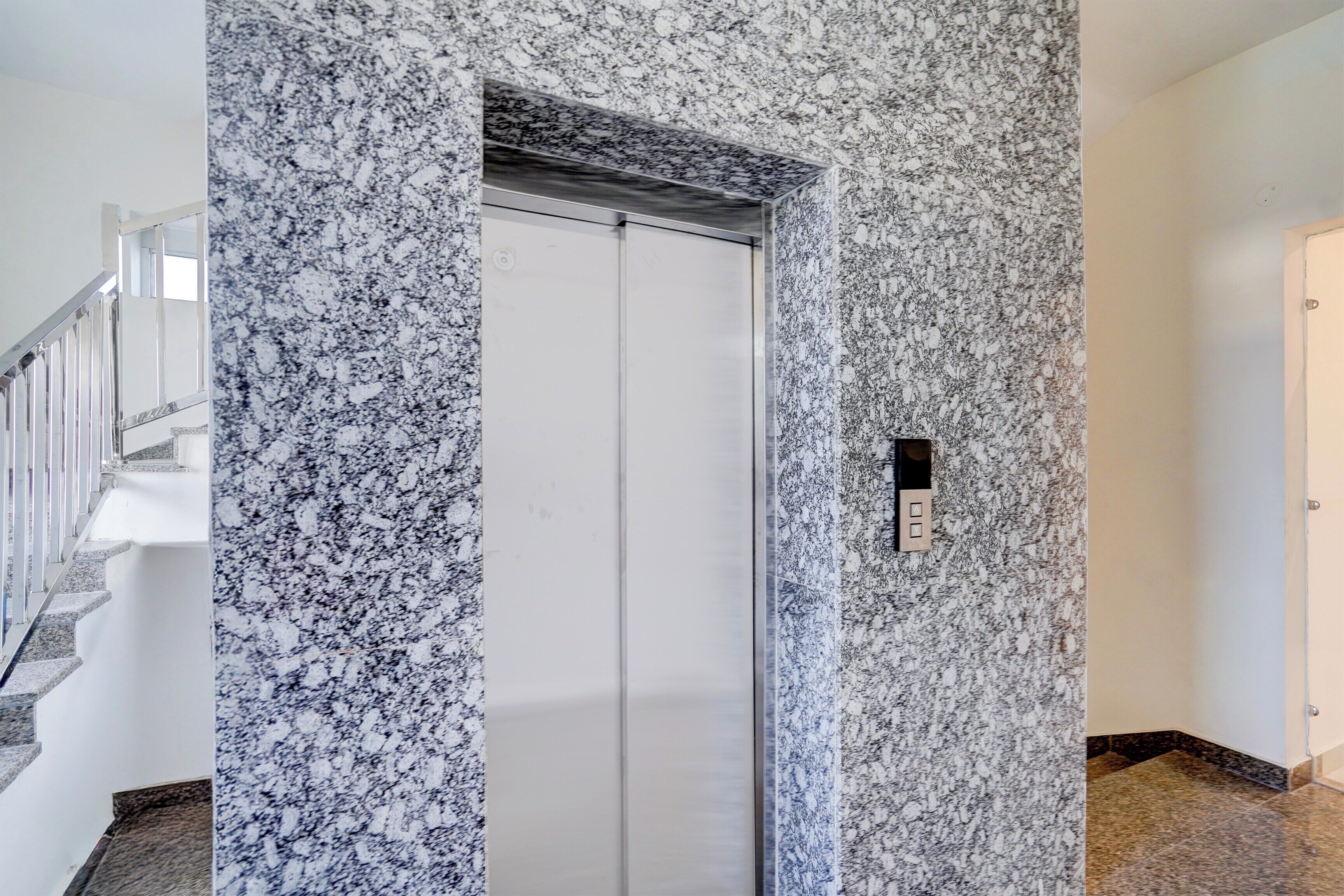 A hallway with a marble wall, a door, and a staircase.