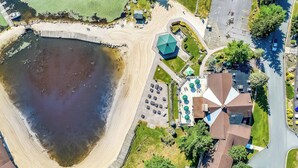 Ett flygbildsbild av en fastighet vid vattnet med en swimmingpool, en parkeringsplats och en lusthus.