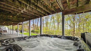 Ett område med ett bubbelbad, ett tak av trä och stora fönster med utsikt över ett skogsområde.