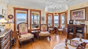 Ein Zimmer mit aufwendiger Holzvertäfelung, einem großen Erkerfenster mit Blick und einer klassischen Chandelier.