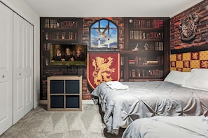 Un dormitorio con una estantería, televisión y cama.