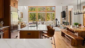 Une cuisine moderne dotée d’un grand îlot central, de meubles en bois et d’un mur d’accent en pierre.