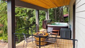 Un espace extérieur abrité comprenant un jacuzzi, un foyer et une table avec des chaises.