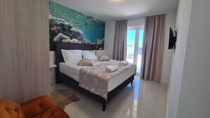 A hotel room with a bed, a large mural of an underwater scene, a ceiling light, and a view of the outdoors through a sliding door. - New villa Angelo 2025 ( family and pet friendly) (Privlaka)