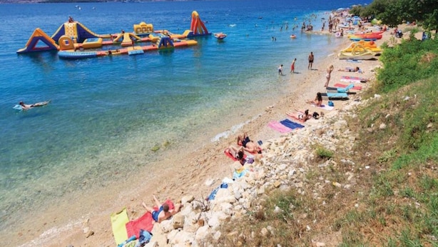 A beach with inflatable water toys and people swimming. - Cozy Apartment Near Raslina Beach (Sibenik)