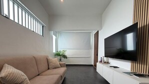 En moderne stue med sofa, fladskærms-tv og en plante.