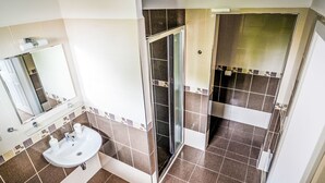 A modern bathroom with a glass shower enclosure, a sink, and a mirror.