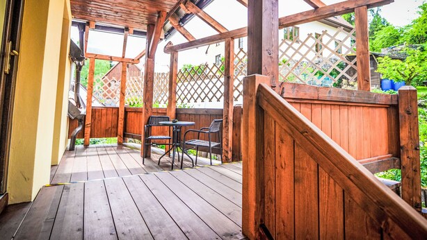 A wooden deck with a pergola, a table and chairs, and a wooden fence.