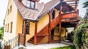 A two-story house with a wooden staircase, a balcony, and a tiled roof.