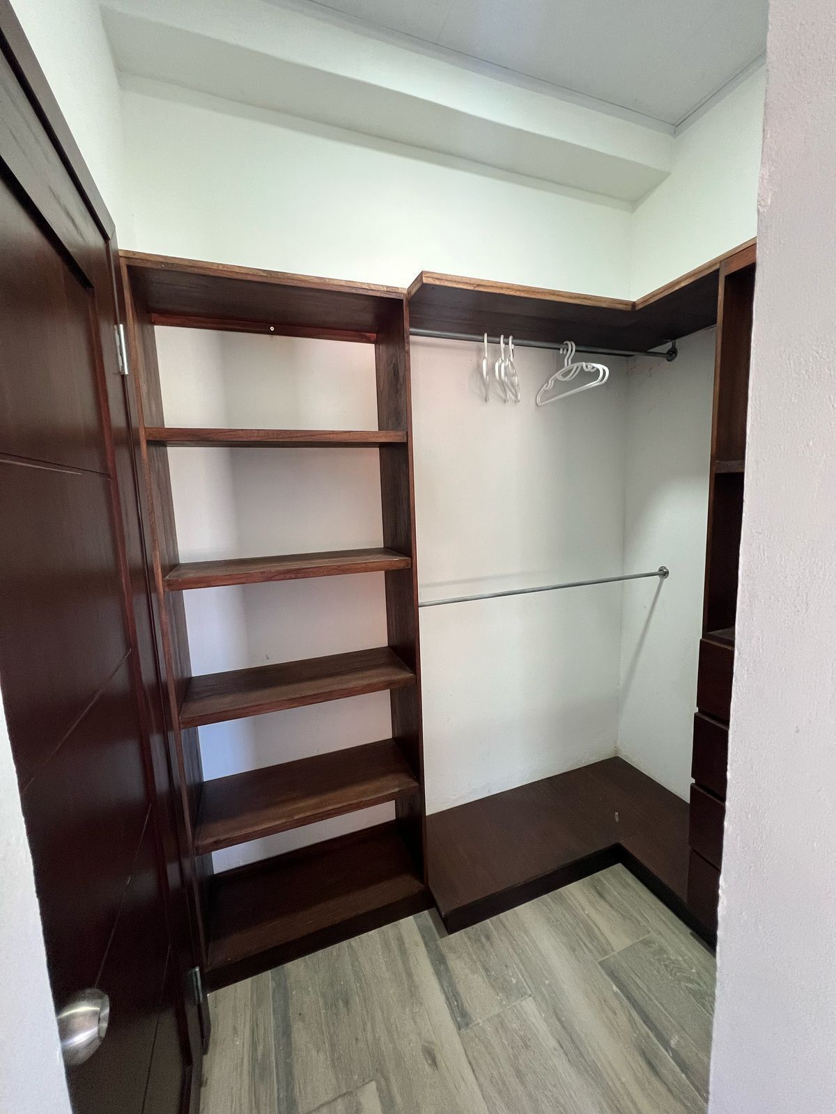 Ein begehbarer Kleiderschrank mit Holzböden und einer Kleiderstange.