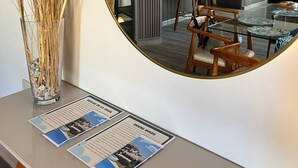 A dining area with a round mirror reflecting the kitchen, a vase with dried plants, and a menu on the table.