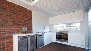 Una cocina moderna con armarios blancos, pared de ladrillo, horno empotrado y ventana.