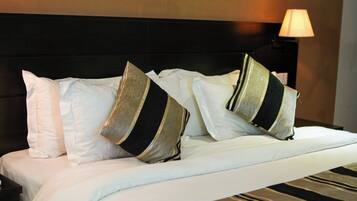 A neatly made bed with white and striped pillows, a black headboard, and a lamp on the side.