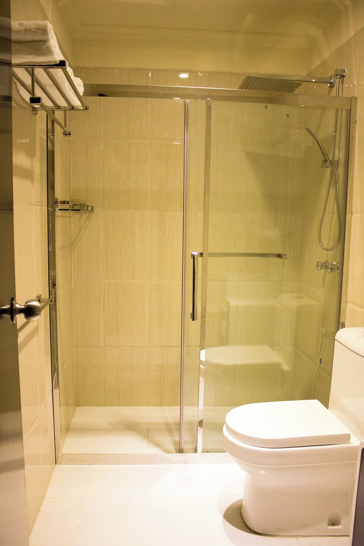 Een moderne badkamer met een douchecabine van glas, een wit toilet en een handdoekhouder.