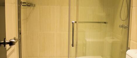 A modern bathroom with a glass-enclosed shower, a white toilet, and a towel rack.