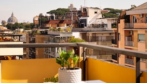 A balcony with a table, a potted plant, and a view of a cityscape including a dome and residential buildings.
