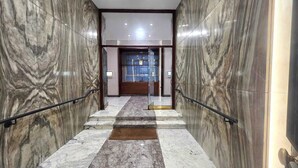 A marble-floored corridor with glass doors leading to a room.