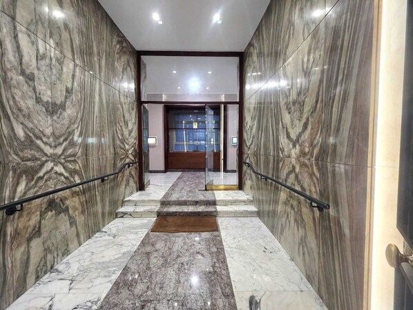 A marble-floored corridor with glass doors leading to a room.