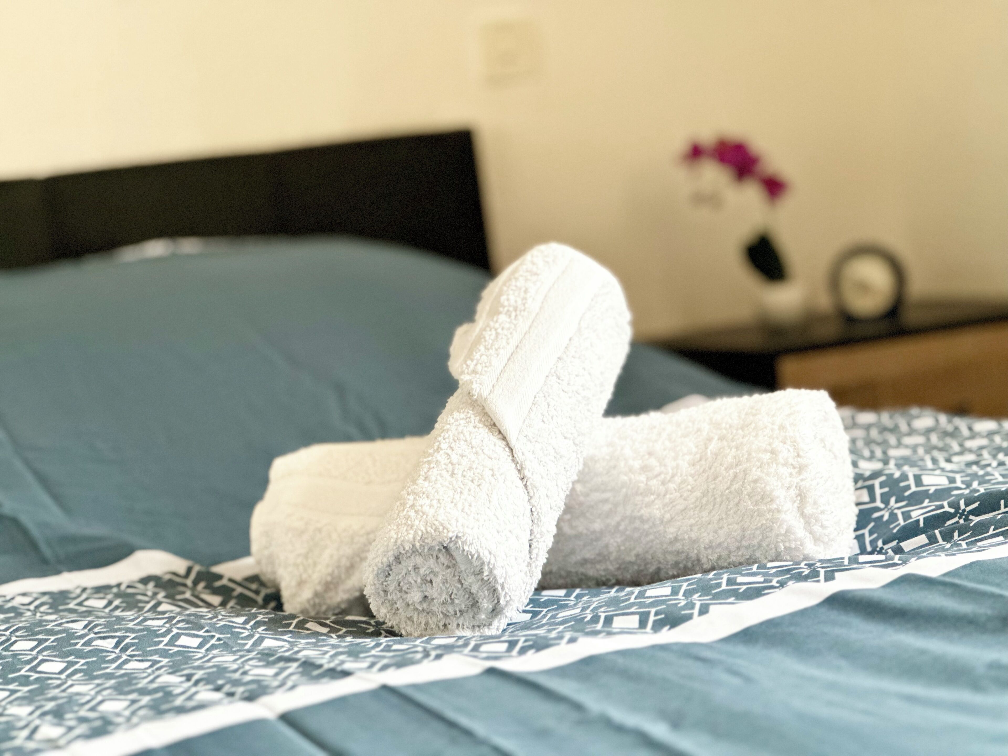 A neatly made bed with a blue bedspread and a patterned pillow.